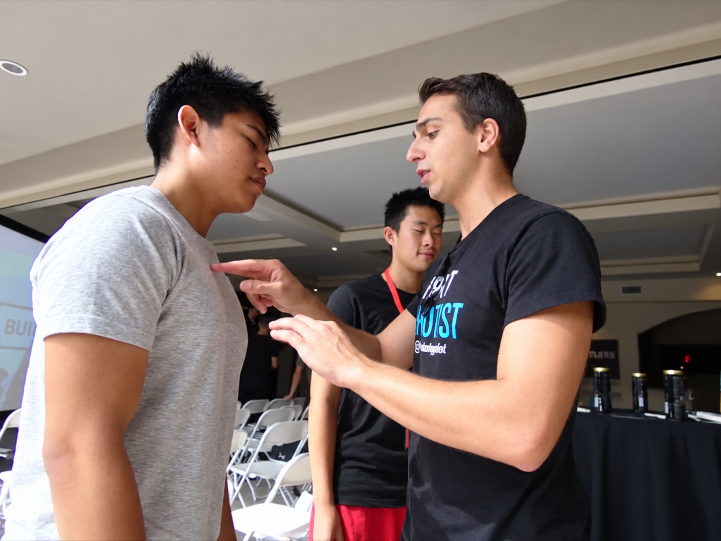 Tyler beside a different participant with closed eyes and a lowered head during a demonstration.
