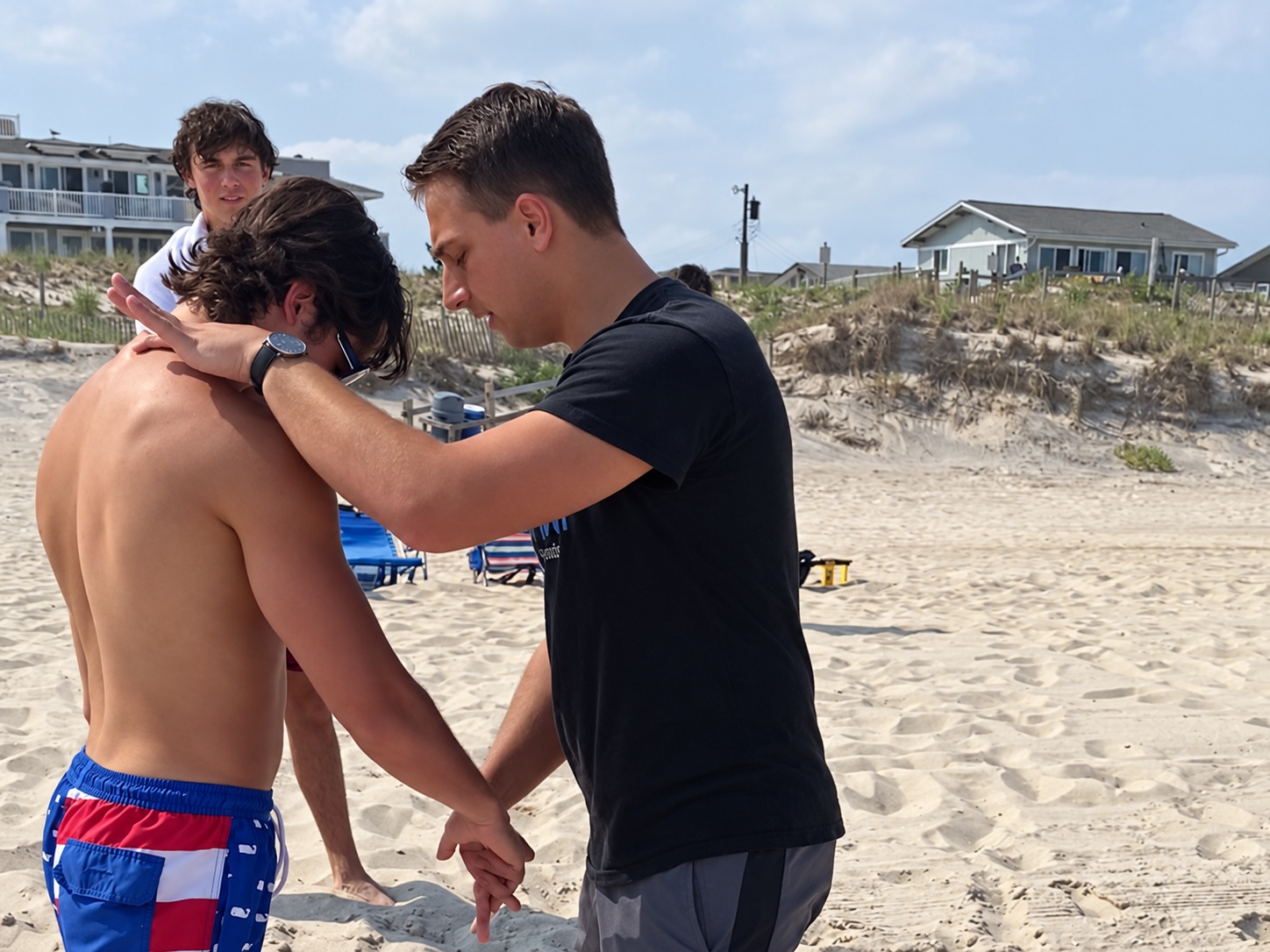 Tyler guiding a beach demonstration beside a participant with their head lowered.